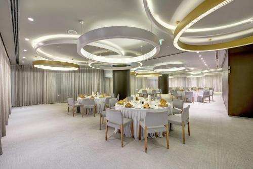 a dining room with white tables and white chairs at The Act Hotel Sharjah in Sharjah