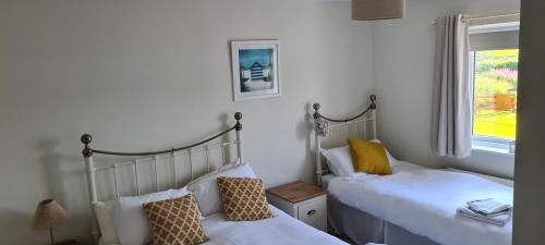 a bedroom with two beds and a window at Cromlech Cottage in Portnoo