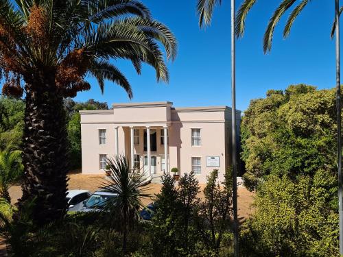 a pink building with palm trees in front of it at Bell Rosen Guest House in Bellville