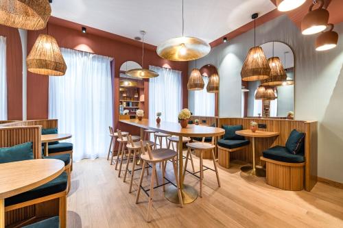 a restaurant with tables and chairs and pendant lights at O.Lysée Hotel in Paris