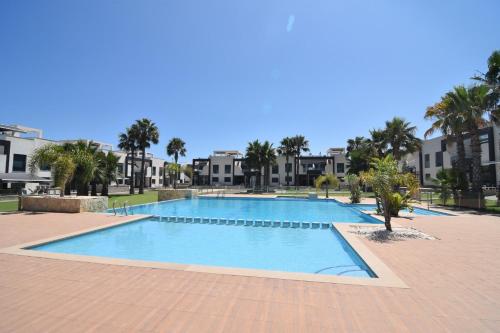 a large swimming pool with palm trees and buildings at Oasis Beach in Orihuela