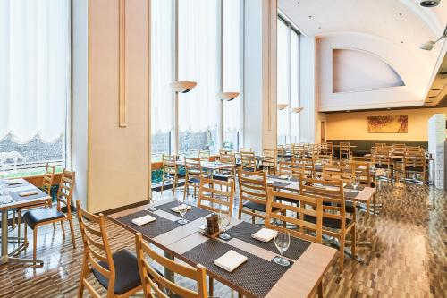 ein Restaurant mit Tischen und Stühlen und großen Fenstern in der Unterkunft Hotel Tokyo Garden Palace in Tokio