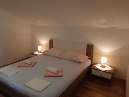 a bedroom with a large bed with two lamps on it at Apartments Nikola Caska in Novalja
