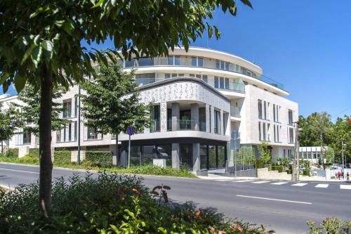 a large white building on the side of a street at Spa Residence Carbona Hévíz - Relax, Sissi Apartmanok in Hévíz