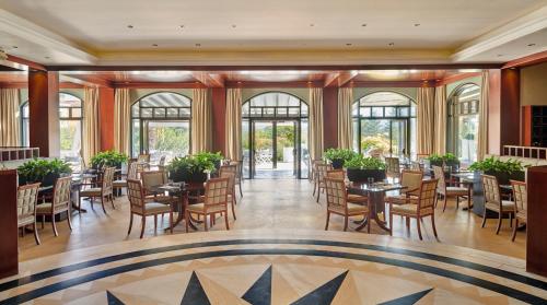 a dining room with tables and chairs and windows at Hyatt Regency Thessaloniki in Thessaloniki