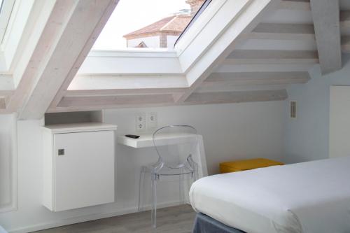 a bedroom with a white bed and a skylight at Hotel Alda San Bieito in Santiago de Compostela