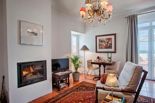 a living room with a fireplace and a chandelier at Casa da Moira in Avis