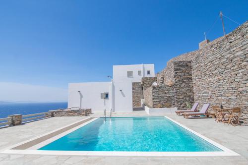 a swimming pool in front of a building with the ocean at Kea Alya luxury living Villa with pool in Melissaki