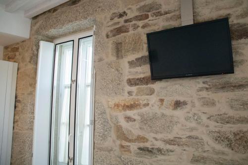 a flat screen tv on a stone wall with a window at Hotel Alda San Bieito in Santiago de Compostela