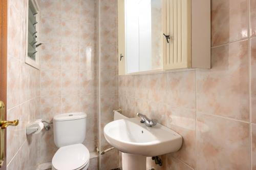 La salle de bains est pourvue de toilettes blanches et d'un lavabo. dans l'établissement Céntrico apartamento cerca de playa y tren a Barcelona para 6 pax, à Premiá de Mar