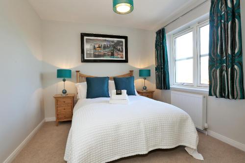 a bedroom with a bed with blue pillows and a window at Town and Country Birchlee Road Apartments in Inverurie