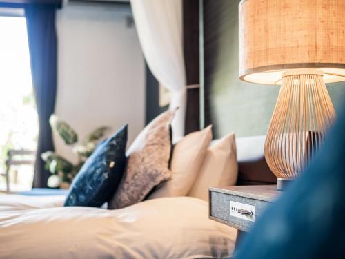 a bedroom with a bed with pillows and a lamp at ザ・ビーチテラスホテルアオ石垣 in Ishigaki Island