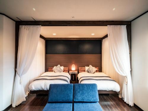 two beds in a room with curtains and a couch at ザ・ビーチテラスホテルアオ石垣 in Ishigaki Island