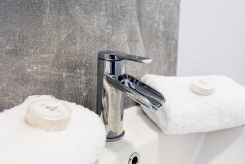 a bathroom sink with a faucet and towels at Wrexham Central Stay - Apartment Six in Wrexham