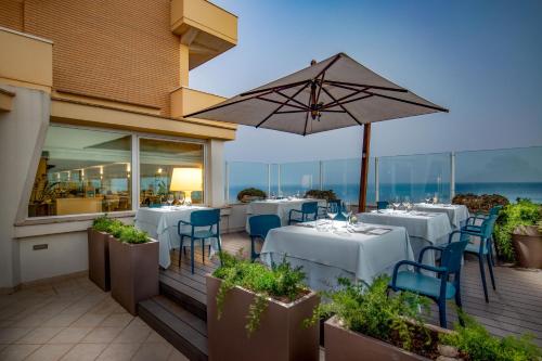 a restaurant with white tables and chairs and an umbrella at Hotel Miramare in Latina