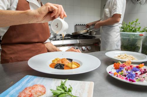 a person standing in a kitchen with two plates of food at Hotel Miramare in Latina