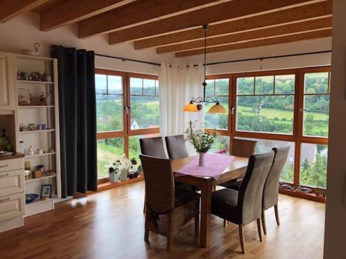 a dining room with a table and chairs and windows at Haus Leenja in Beverungen