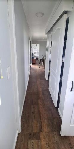 a long hallway with white walls and wooden floors at Casetta del Fuoco - Eco Container Cottage in Plettenberg Bay