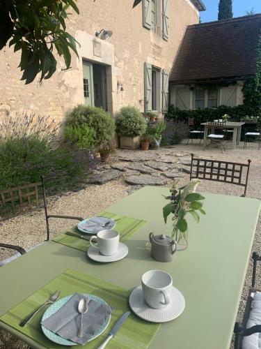 a green table with two cups and plates on it at Manoir de Malagorse in Cuzance