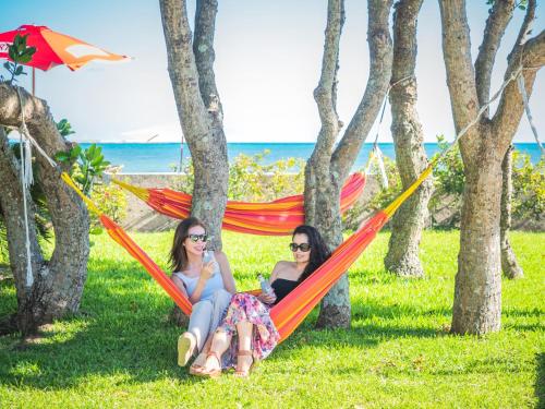 石垣島的住宿－ザ・ビーチテラスホテルアオ石垣，两个女人坐在草地上的吊床上