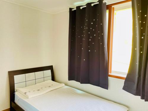 a bedroom with a bed and a window with stars at Backpackers In Yeosu in Yeosu