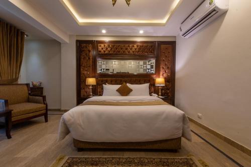 a bedroom with a large bed and a chair at Envoy Continental Hotel, Islamabad in Islamabad