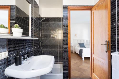 Łazienka z białą umywalką i czarnymi kafelkami w obiekcie Casa Platano - Private pool - Ocean View - BBQ - Garden - Terrace - Free Wifi - Child & Pet-Friendly - 4 bedrooms - 8 people w mieście Poris de Abona
