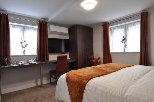 a hotel room with a bed and a desk and window at King Hotel Tenterden in Tenterden