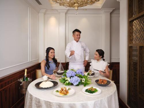 a man and two women sitting around a table with food at InterContinental Singapore by IHG in Singapore