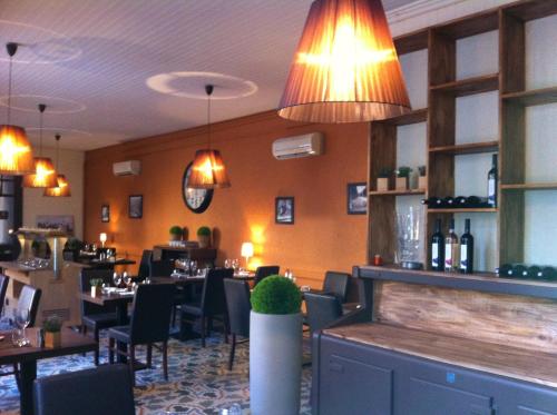 a dining room with tables and chairs and lights at Logis Hotel Le Clos Des Oliviers in Bourg-Saint-Andéol