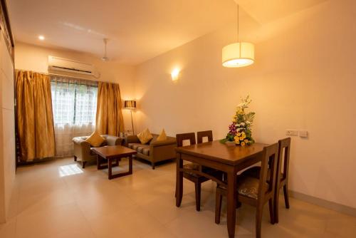 a living room with a dining table and a couch at La-Paz Gardens Beacon Hotel - Vasco da Gama Goa in Vasco Da Gama