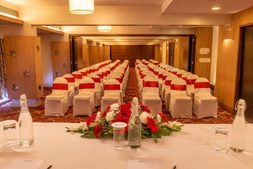 a room with a long table with white chairs and flowers at La-Paz Gardens Beacon Hotel - Vasco da Gama Goa in Vasco Da Gama