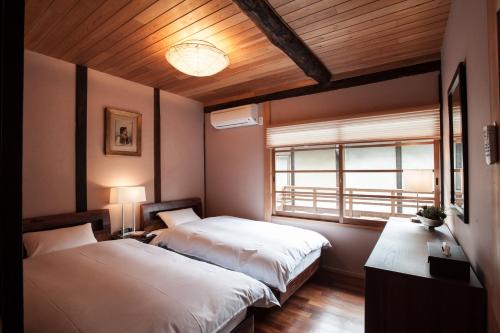 a bedroom with two beds and a window at Kiyomizu Machiya Inn in Kyoto