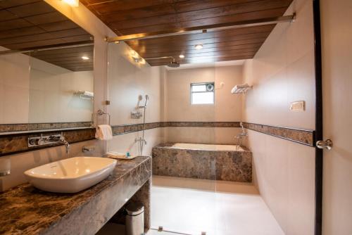 a bathroom with a sink and a tub at La-Paz Gardens Beacon Hotel - Vasco da Gama Goa in Vasco Da Gama