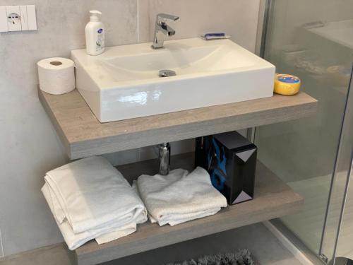 baño con lavabo y toallas en un estante en Case Vacanze Giovanna, en Petrosino