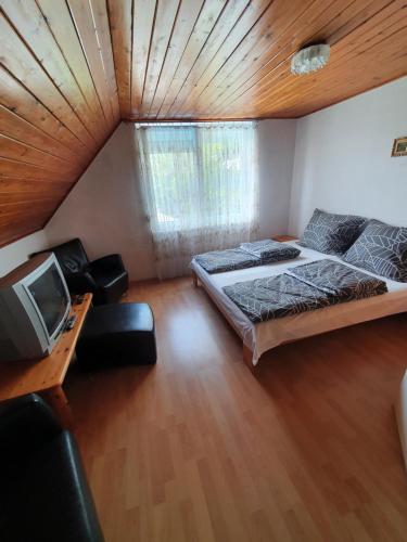 a room with two beds and a television in it at Wolf Vendégház in Balatonkeresztúr