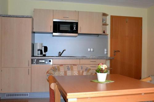阿爾高地區旺根的住宿－Ferienwohnung Kitzelmann，带木桌的厨房和带微波炉的厨房。