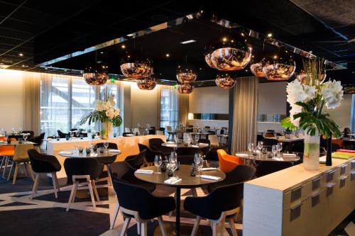 a dining room with tables and chairs and chandeliers at Oceania Paris Roissy CDG in Le Mesnil-Amelot