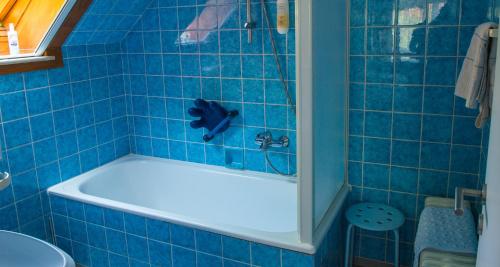 a blue tiled bathroom with a tub and a toilet at Hotel Garni am Eckernweg in Celle