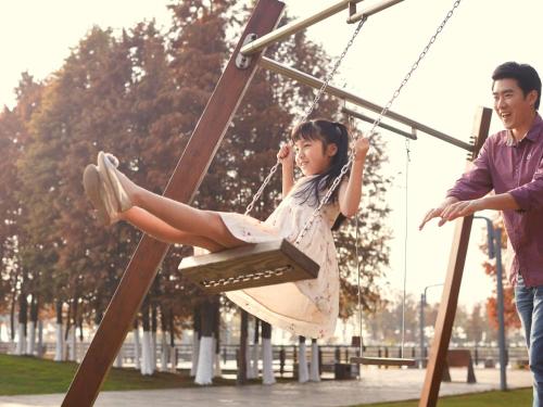 a woman sitting on a swing in a park at Fairmont Yangcheng Lake in Kunshan