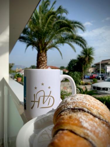 a pastry on a plate next to a coffee cup and a palm tree at Hotel Vallisdea in Sala Consilina