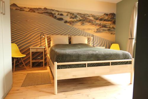 een slaapkamer met een bed met een woestijn muurschildering aan de muur bij Appartement ' Het Zilte'. in Yerseke