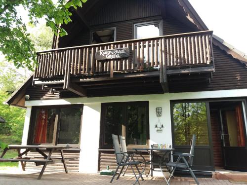 a house with a balcony and a table and chairs at Knusperhaus Gretel in Frankenau