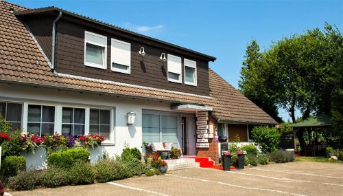 a house with flowers in a parking lot at Hotel Garni am Eckernweg in Celle