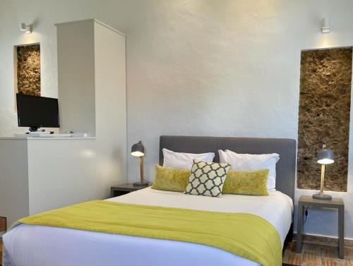 a bedroom with a large bed with a yellow blanket at Casas Do Moinho - Turismo De Aldeia in Odeceixe