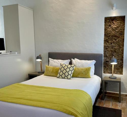 a bedroom with a large bed with green sheets and pillows at Casas Do Moinho - Turismo De Aldeia in Odeceixe