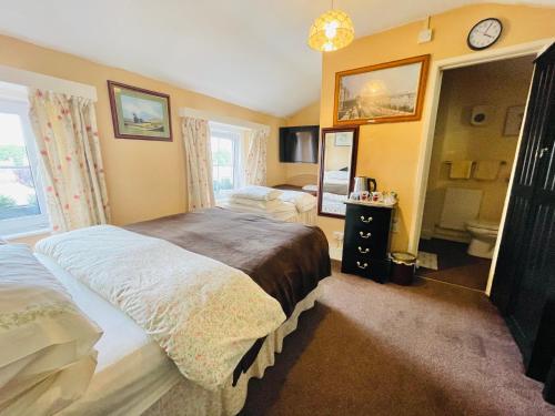 a bedroom with two beds and a bathroom at APSLEY VILLA GUEST HOUSE. in Cirencester