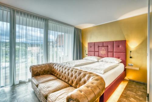 a bedroom with a large bed and a leather couch at Rocket Rooms Velden in Velden am Wörthersee