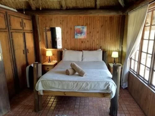 a bedroom with a bed with two lamps and two windows at ThabaNkwe Bushveld Inn in Thabazimbi