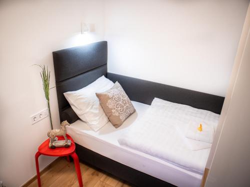 a bed with a black headboard and a red table at Ugo Apartman in Halászi